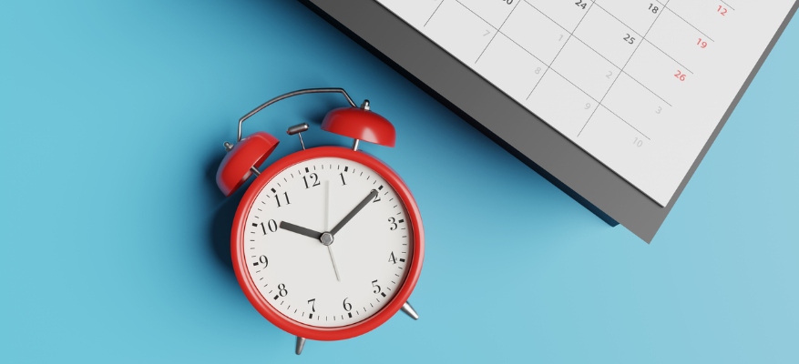 clock next to calendar on a blue table